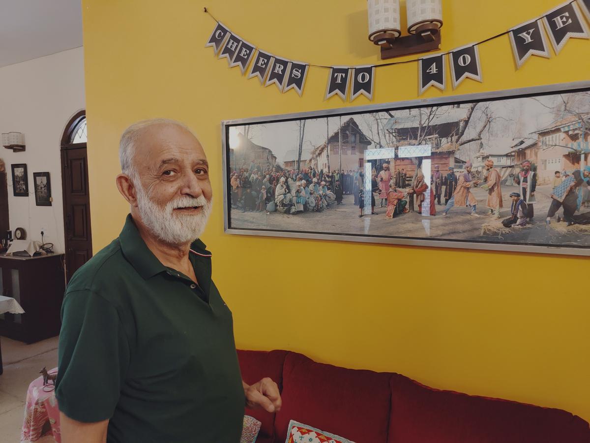 M.K. Raina poses in front of a photograph of his adaptation of King Lear in Bandh Pather form of Kashmiri folk theatre